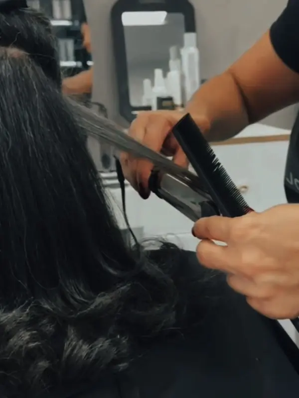 Stylist using a flat iron on a client's long hair